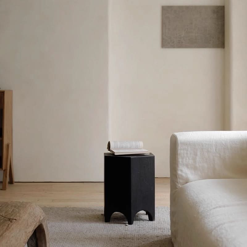 Black hexagonal side table with minimalist wood legs, accenting a modern living room.