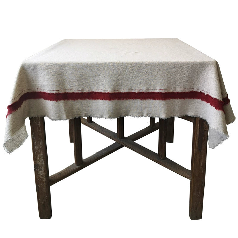 Rustic linen tablecloth with red striped border on a wooden table.