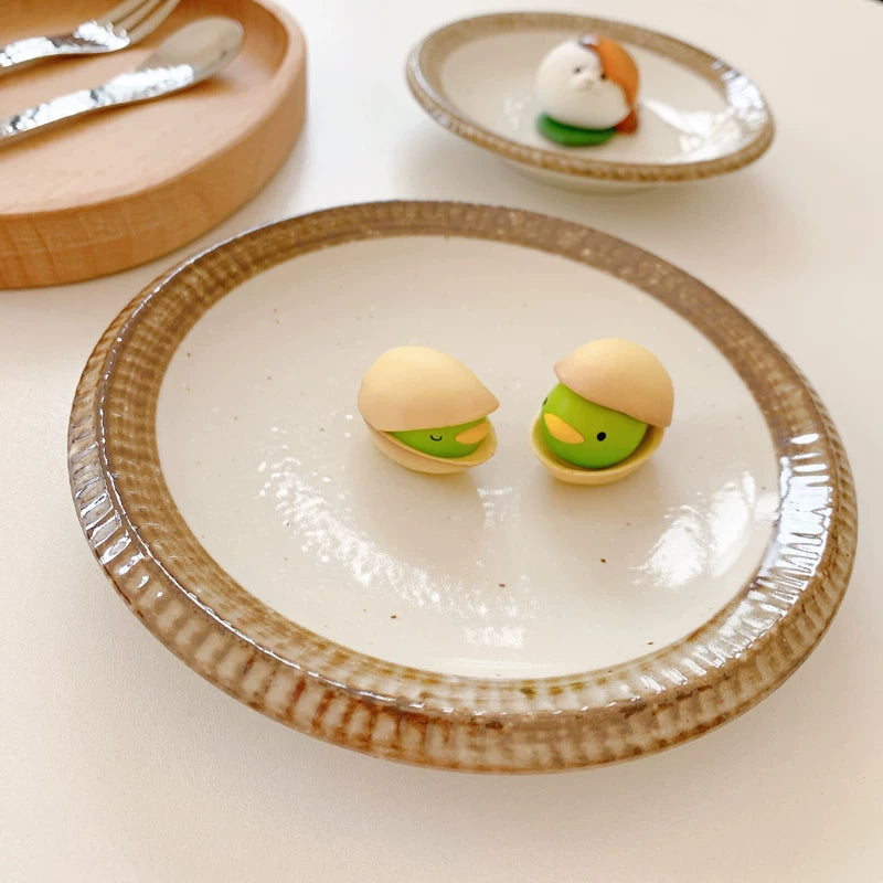 Small ceramic plate holding two small, cute pistachio-themed food miniatures.