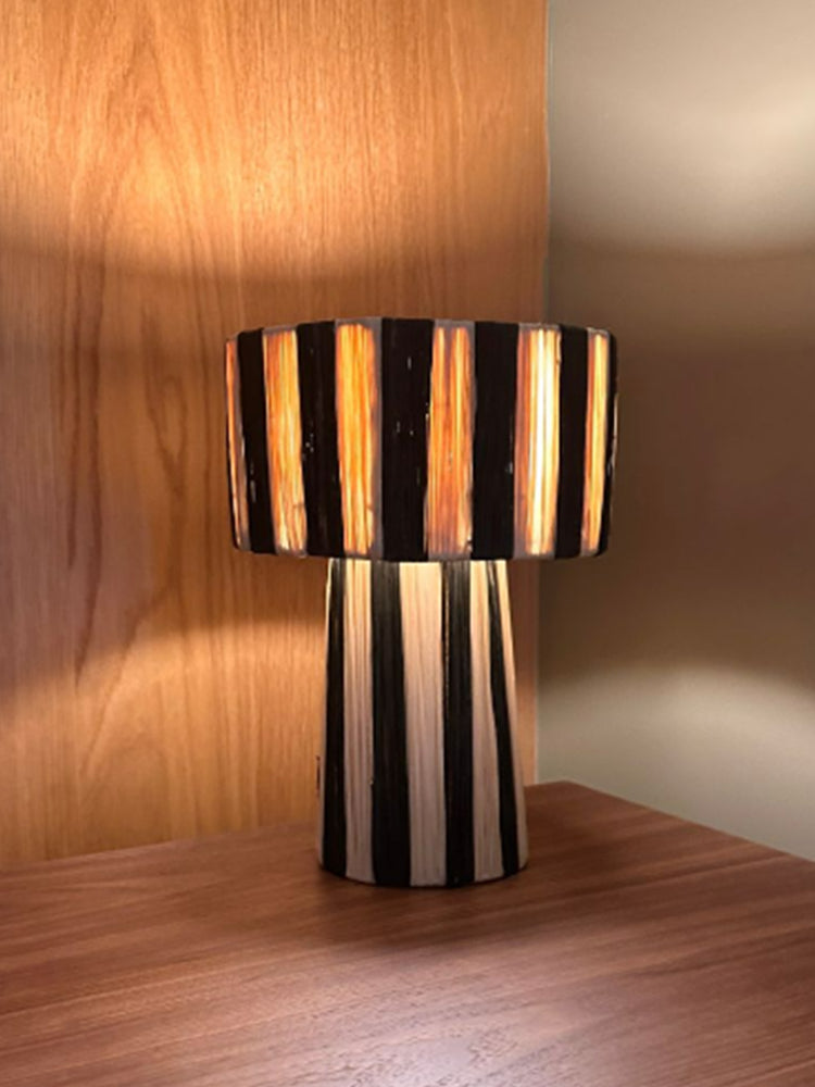 Moroccan Raffia Striped Desk Lamp, black and cream raffia, on wooden table.