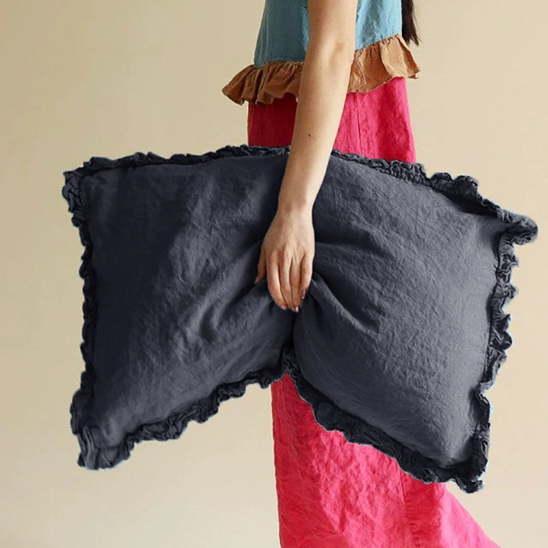 Dark grey rustic linen pillowcases with frills, set of 2, held by a person.