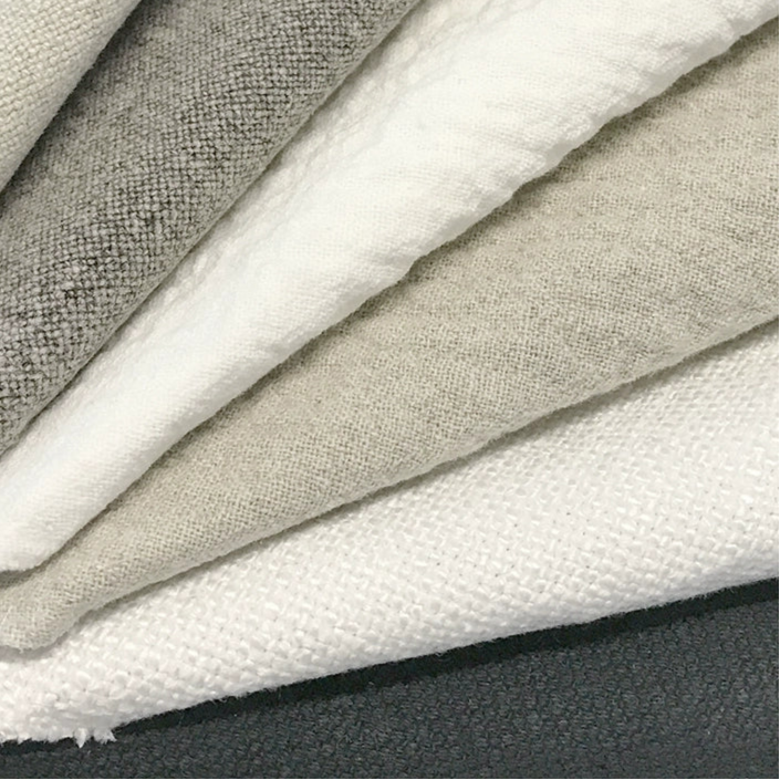 Stacked linen fabrics in various shades of beige, gray, and white.  Natural linen texture.