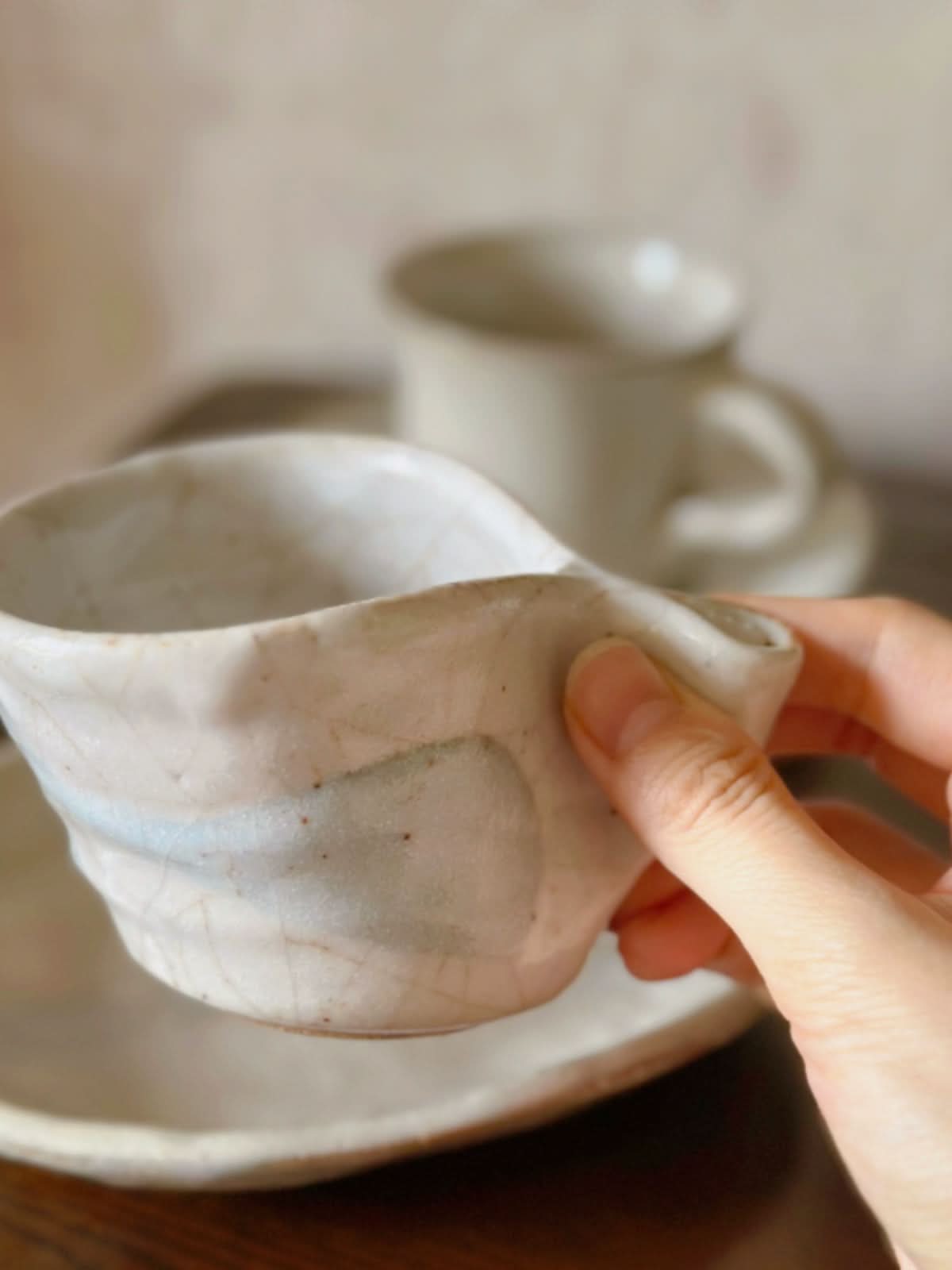 Hand-thrown Japanese Vintage Teacup and Saucer Set, cream ceramic, textured, in hand.