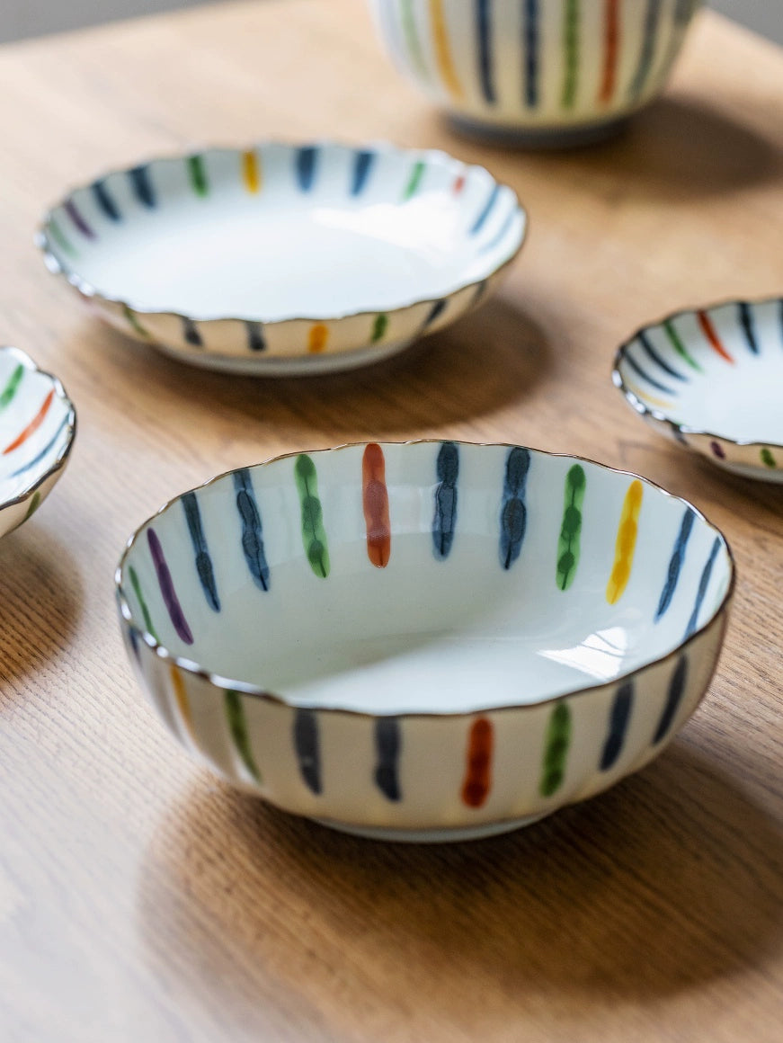 Colorful Striped Japanese Dinnerware Set: ceramic bowls & plates with vertical stripes on a wooden table.