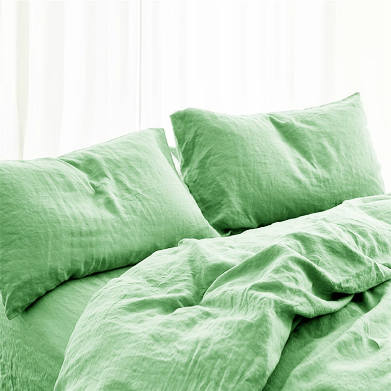 Soft green natural linen bedding set with pillows on a bed.