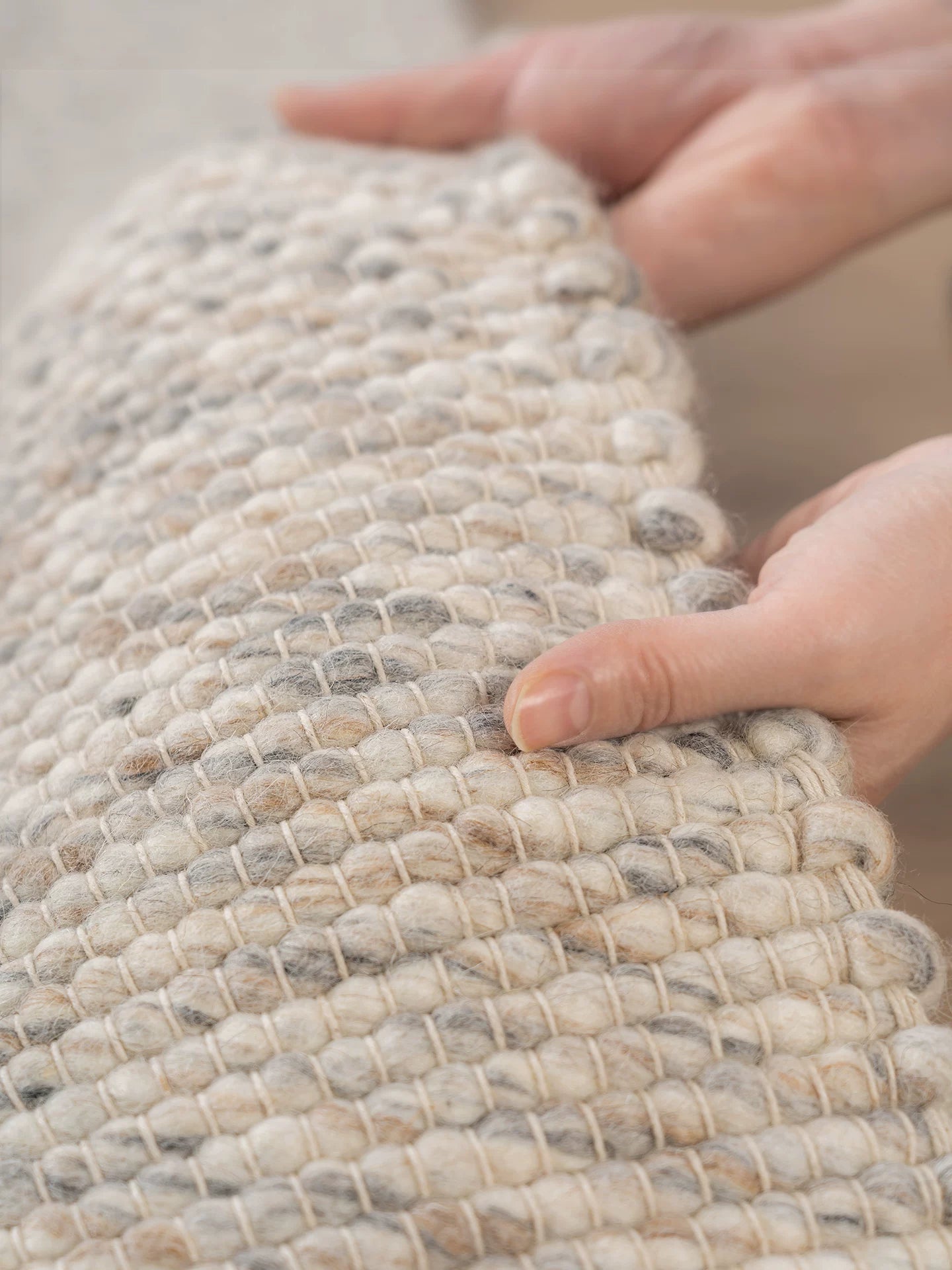 Hands demonstrating thick texture and flexibility of wool rug