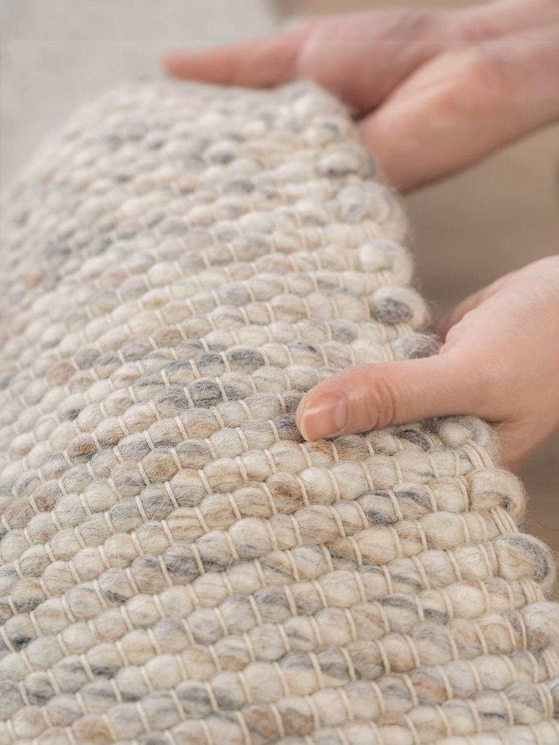 Hands demonstrating thick texture and flexibility of wool rug