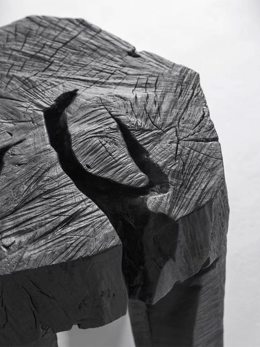 Textured black wood block side table with carved details.