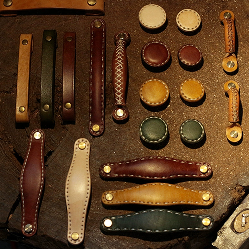 Brown leather drawer pulls and cabinet handles in various rustic styles with brass hardware on wood.