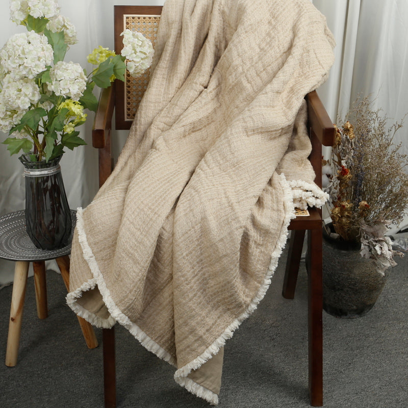 Beige linen cotton throw blanket with white tassels.