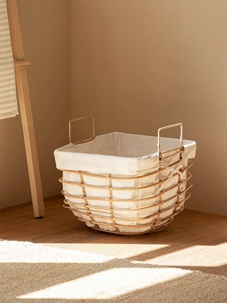 Rattan laundry basket with linen liner in a warm, sunlit room.