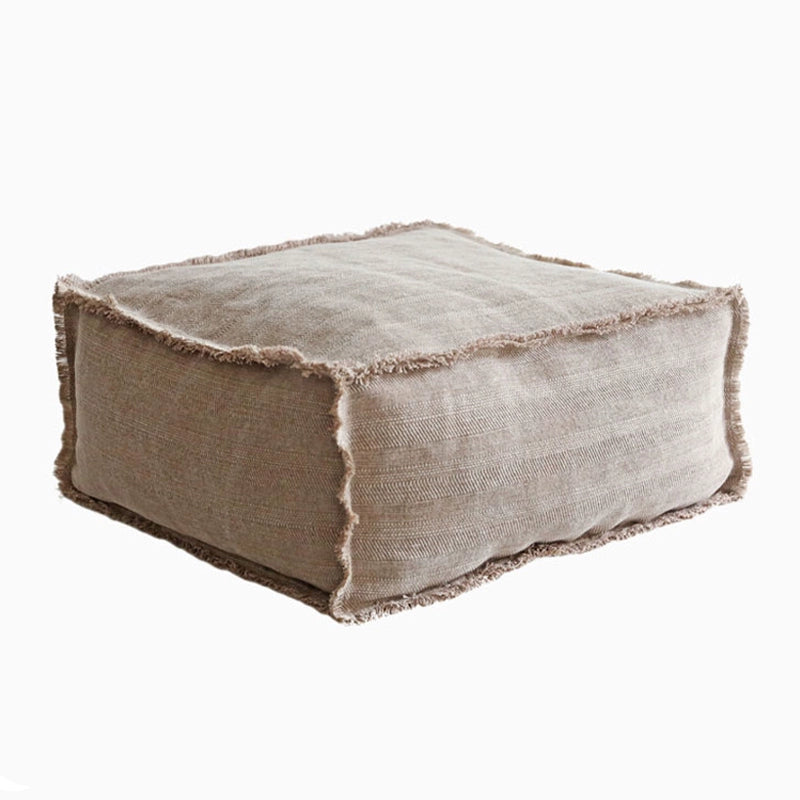 Rustic square fabric ottoman in warm taupe with frayed edges, ideal for living rooms.