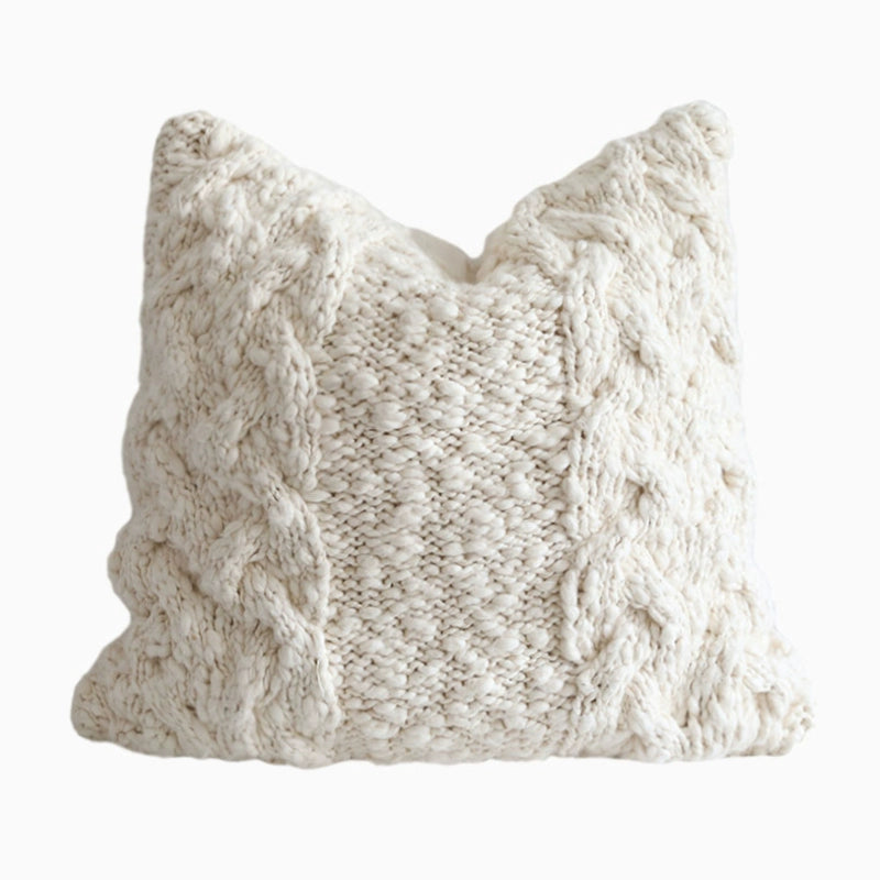 Cream knitted throw pillow with cable knit texture. Cozy decorative pillow.