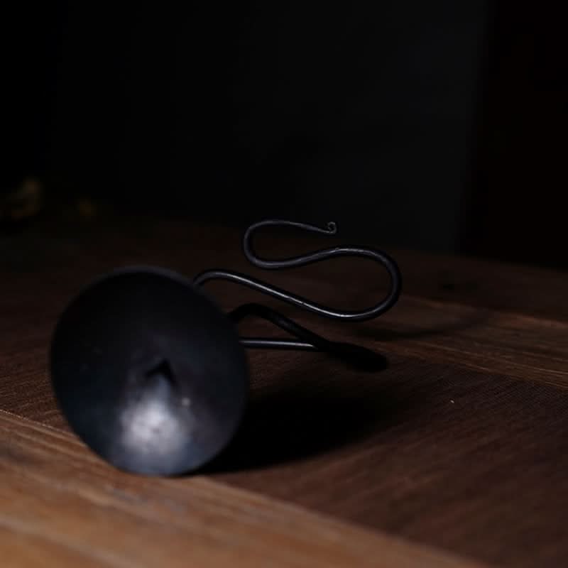 Black metal curved candle holder on rustic wood. Elegant candle stand.