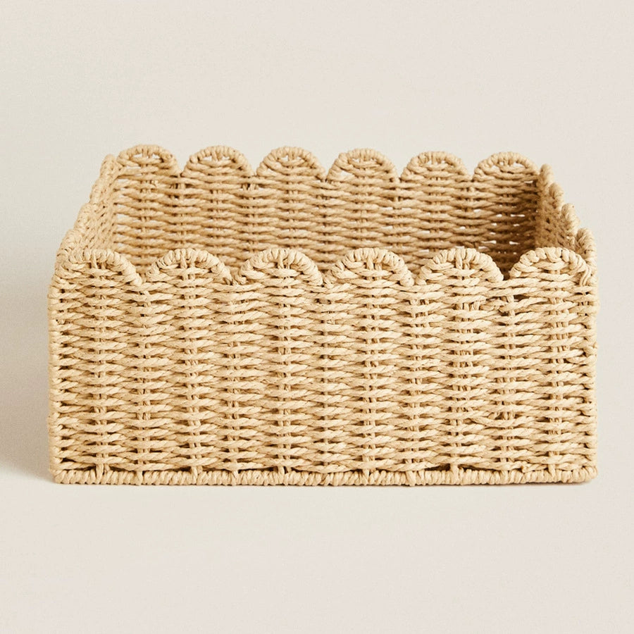 Light beige woven rattan storage basket with scalloped edges.  Square shape, natural material.