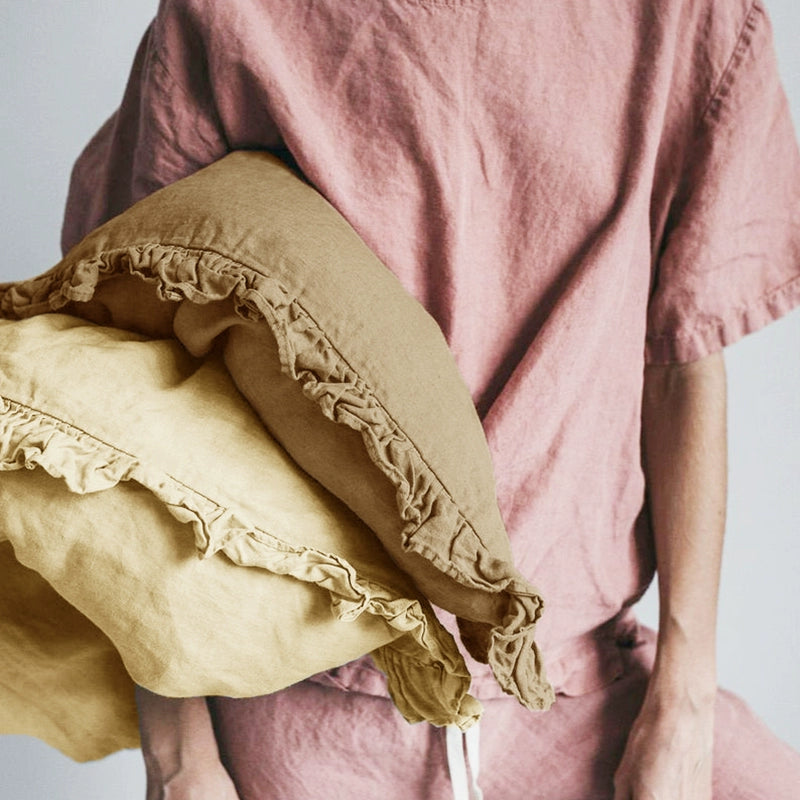 Set of 2 Rustic Linen Pillowcases with Frills in tan and yellow, held by person in pink linen.