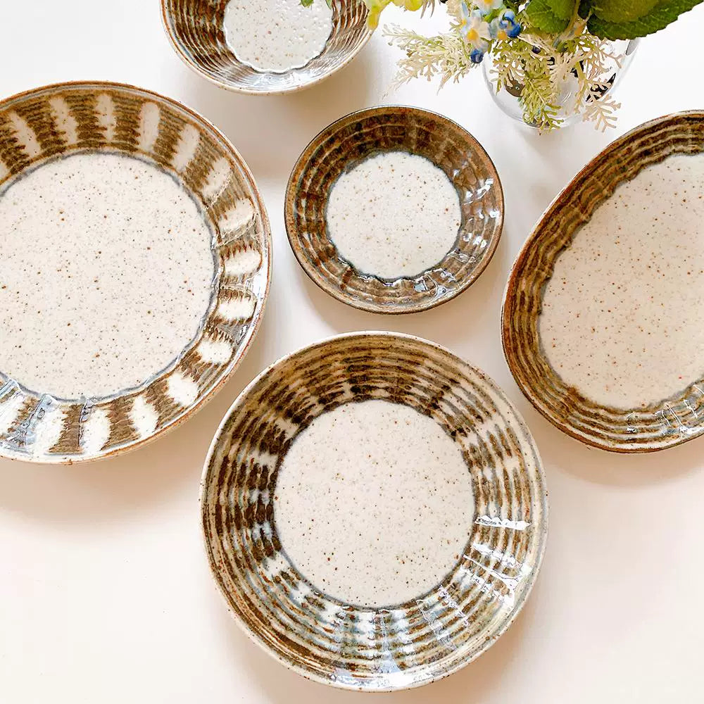 Grouping of several ceramic dishes showing speckled glaze and distinctive dark brown, hand-drawn swirl pattern.