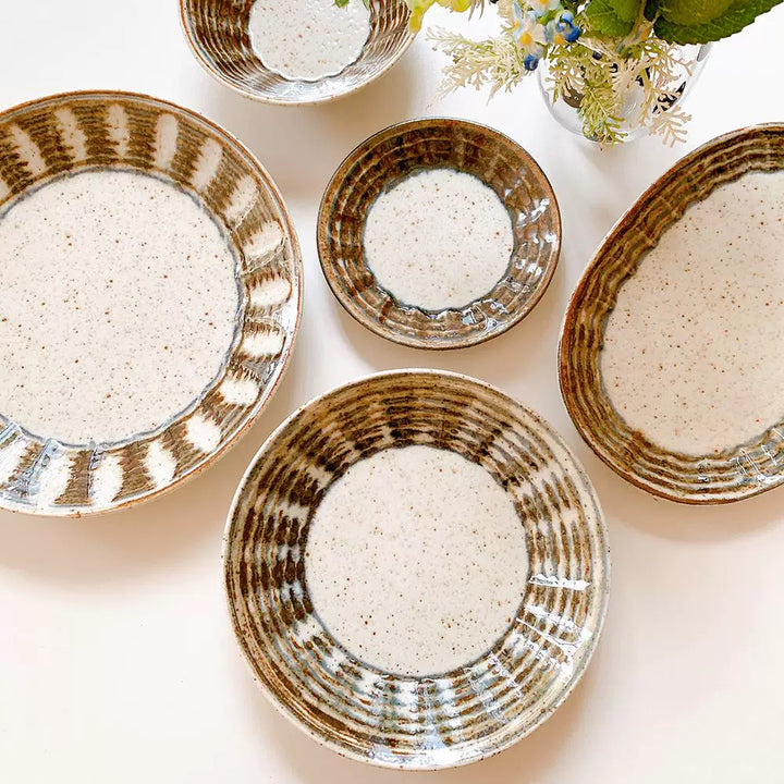 Grouping of several ceramic dishes showing speckled glaze and distinctive dark brown, hand-drawn swirl pattern.
