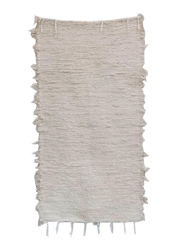 Beige knitted throw blanket with textured lines and frayed edges.  Boho style.