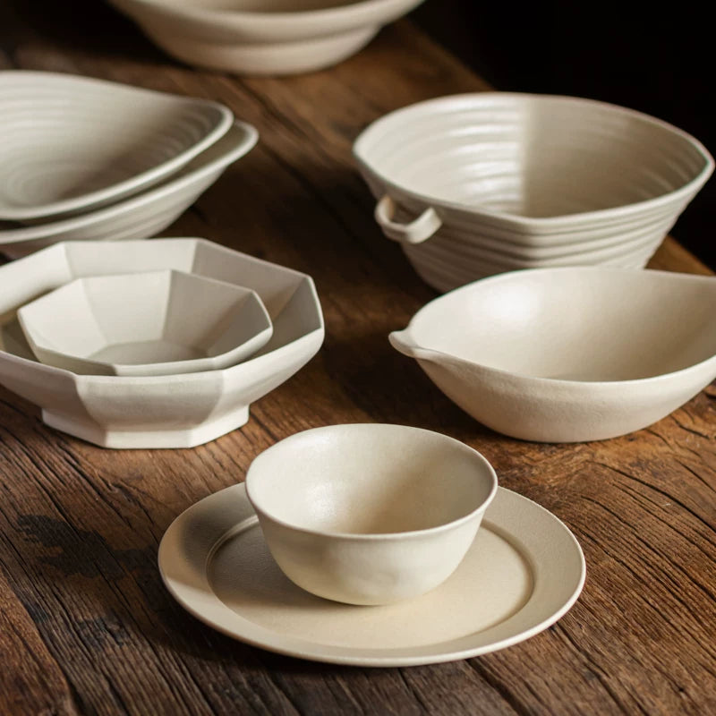 Collection of various white ceramic dishes: hexagonal plates, small bowls, and a small round bowl on a saucer.