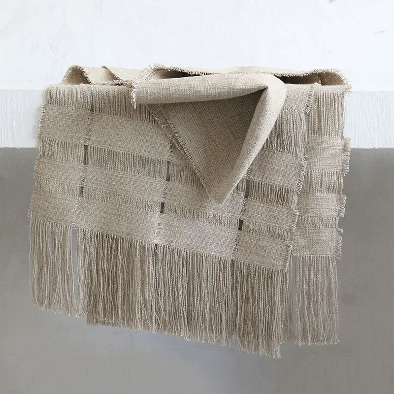 Beige linen table runner with tassels and woven detail, rustic home decor.