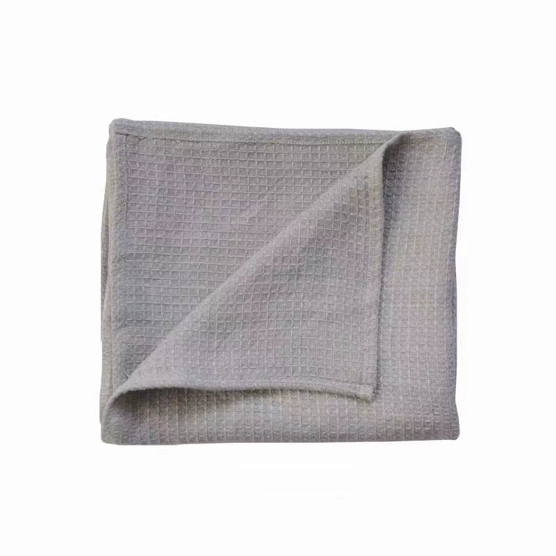 Folded gray waffle weave cotton towel, showcasing a textured grid pattern.