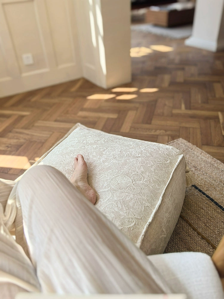 Beige embroidered ottoman pouf with tassels, decorative floor cushion for cozy living rooms and bedrooms.