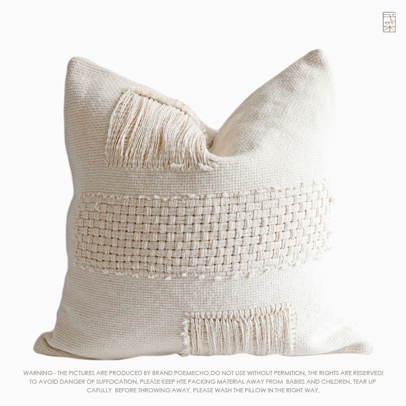 Cream woven throw pillow with fringe detailing, modern boho decor.