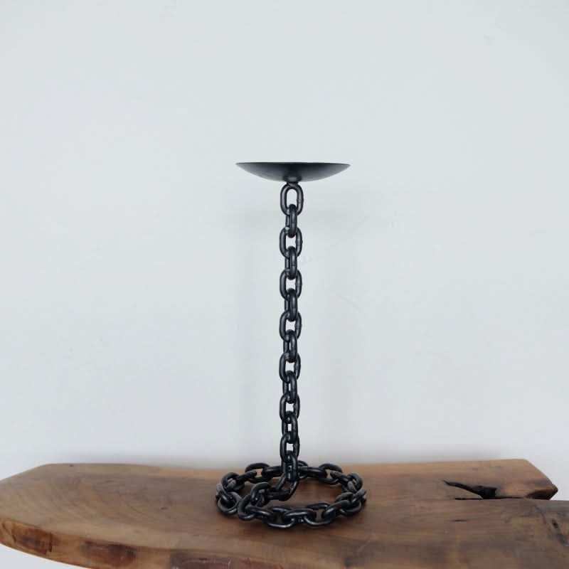 Black metal chain candle holder with a round base, perfect for unique home decor accents.