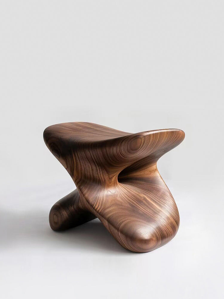 Sculptural walnut wood stool, a modern statement piece, on white background.