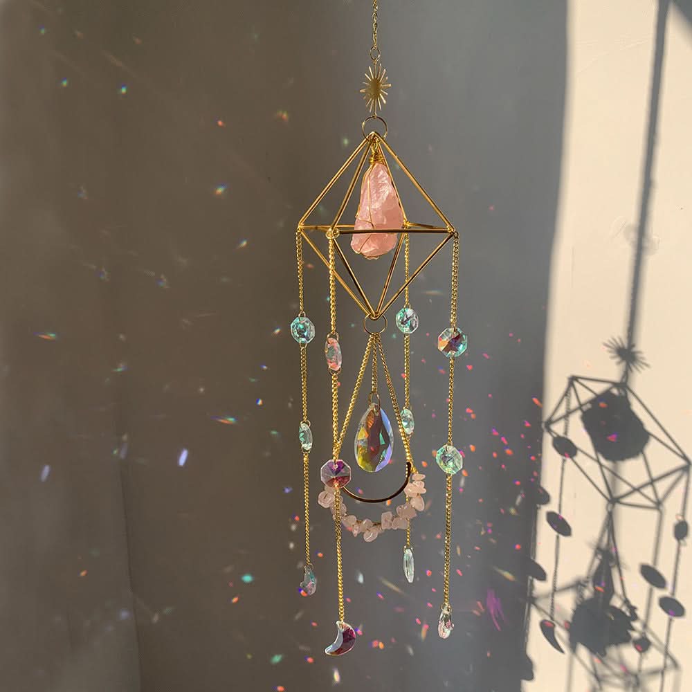 Crystal diamond sun catcher with gold geometric frame, pink rose quartz, and iridescent prisms casting rainbow light.