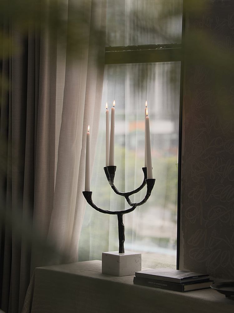Modern Black Metal & Marble Candle Holder with lit white candles by window