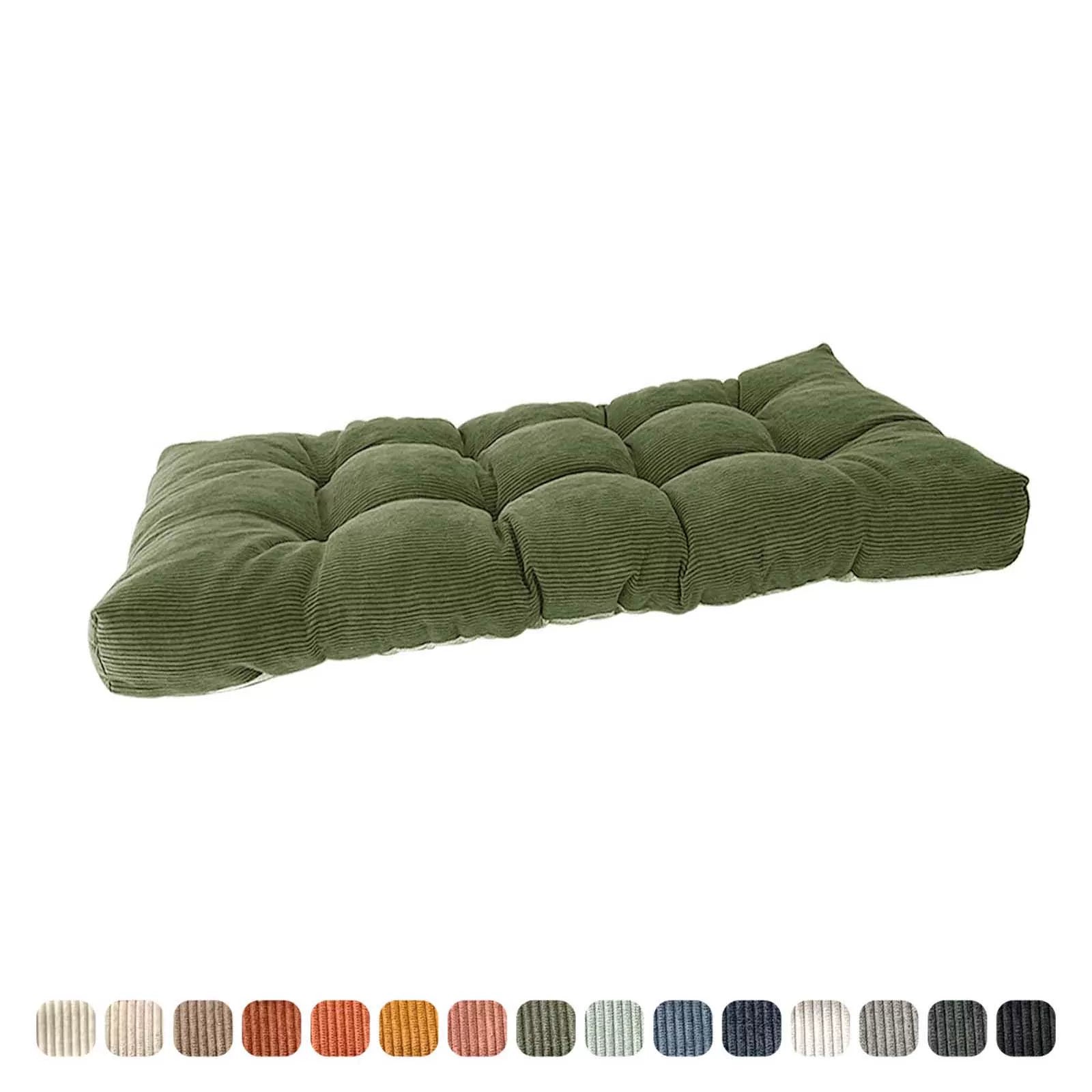 Close-up view of a large, green corduroy tufted seat pad for outdoor furniture.