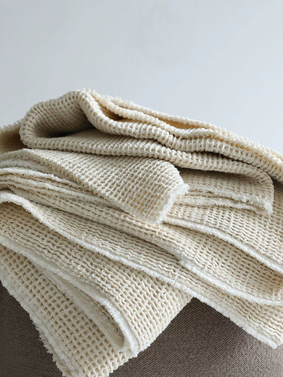 Close-up of Cozy Waffle Knit Linen Throw Blankets, beige waffle texture with frayed edges.