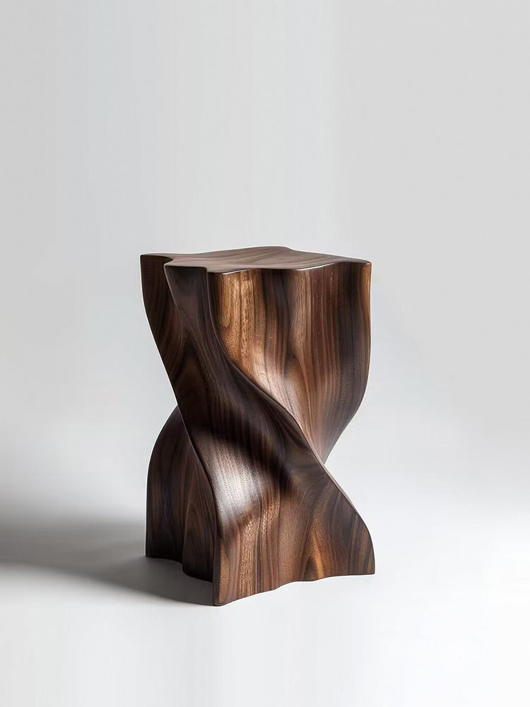 Sculptural walnut wood stool with a modern twisted design on a white background.