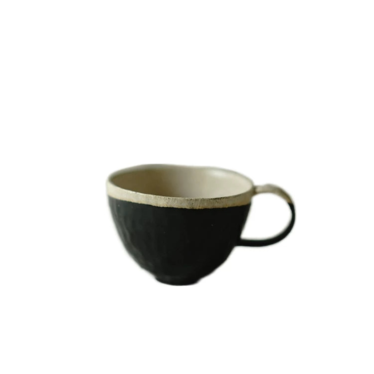 Single handcrafted ceramic teacup with a matte black finish and natural cream interior, isolated on a white background.