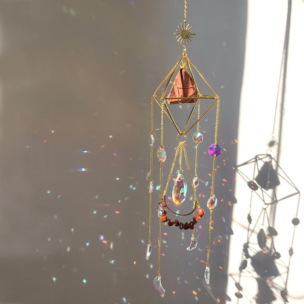 Crystal diamond sun catcher with prism crystals and gold chain, casting colorful light reflections.