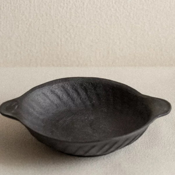Detailed view of a small oval ceramic dish with ridged, scalloped edges and dual handles.