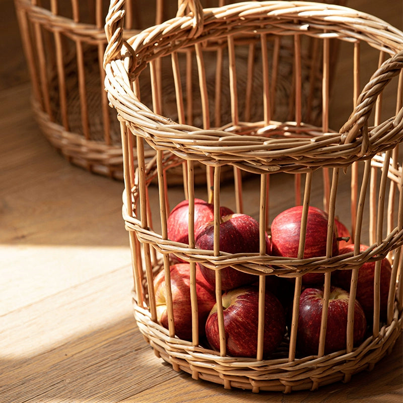 Round woven wicker basket with handles, filled with red apples, home decor.