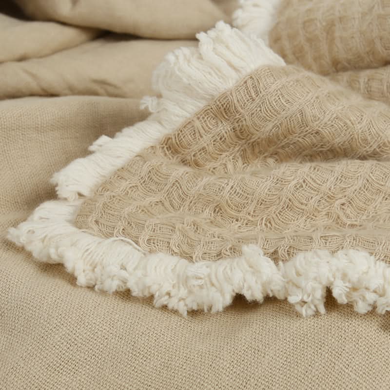 Beige linen cotton throw blanket with tassels, textured weave, neutral home decor.
