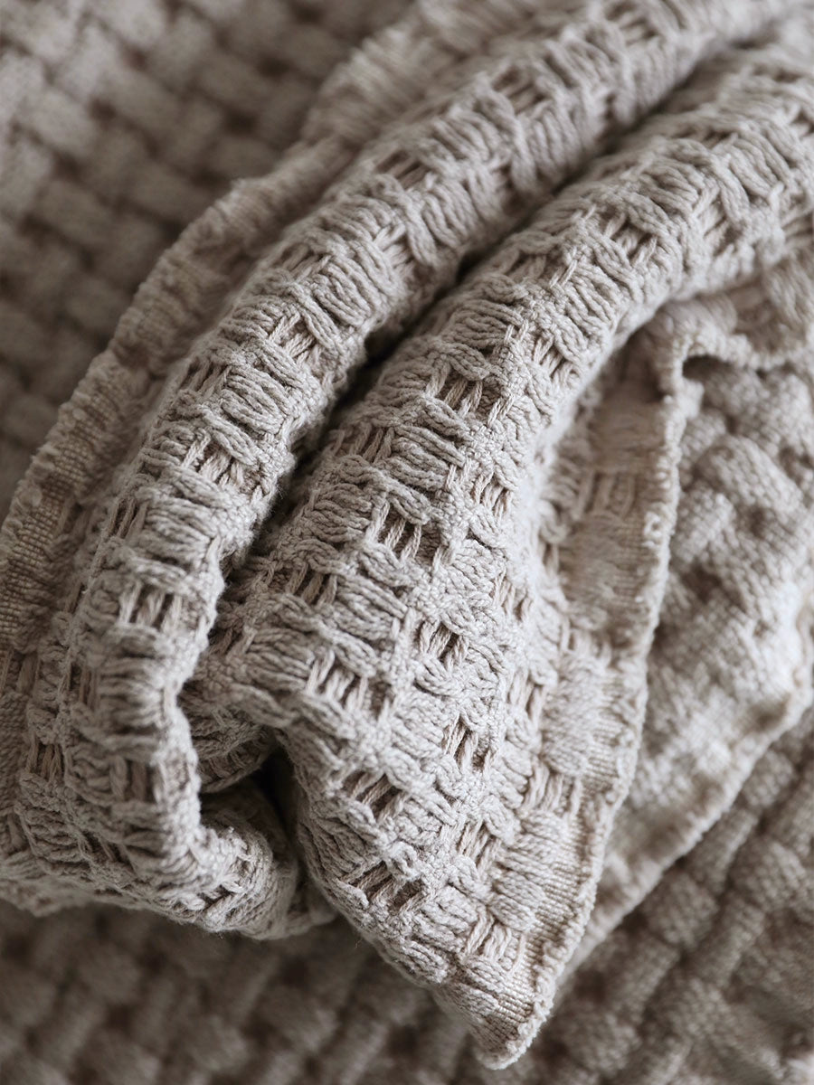 Beige woven cotton throw blanket, close-up.  Textured, grid pattern.