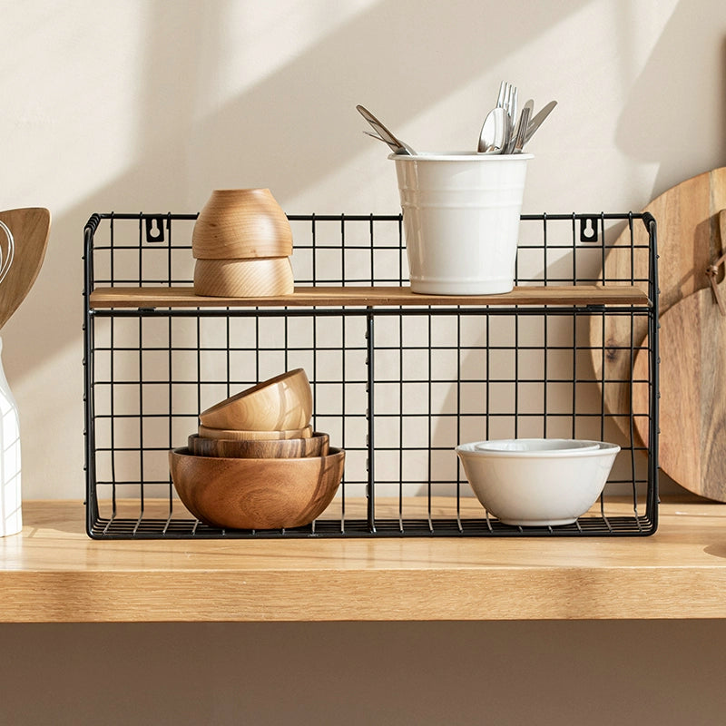 Black metal wire wall shelf with wooden top, double tiered.  Wooden bowls and a white pot on the shelves. Kitchen storage organizer.