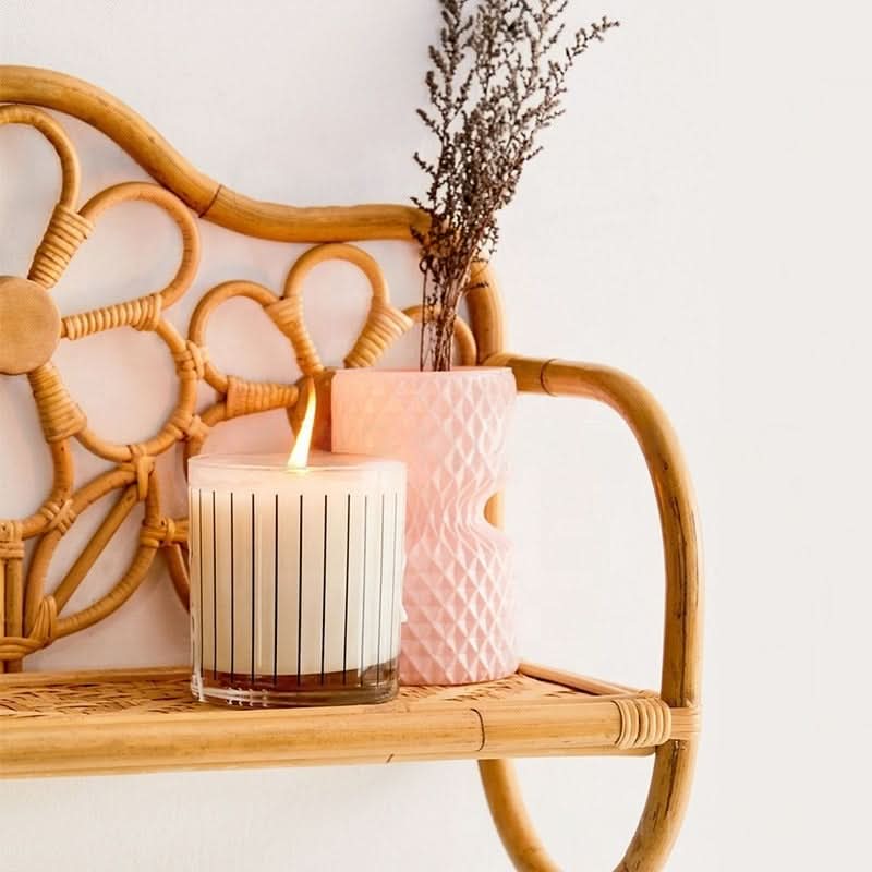 Rattan Wall Shelf With Flower Pattern: lit candle, pink vase with dried flowers on natural wood shelf.