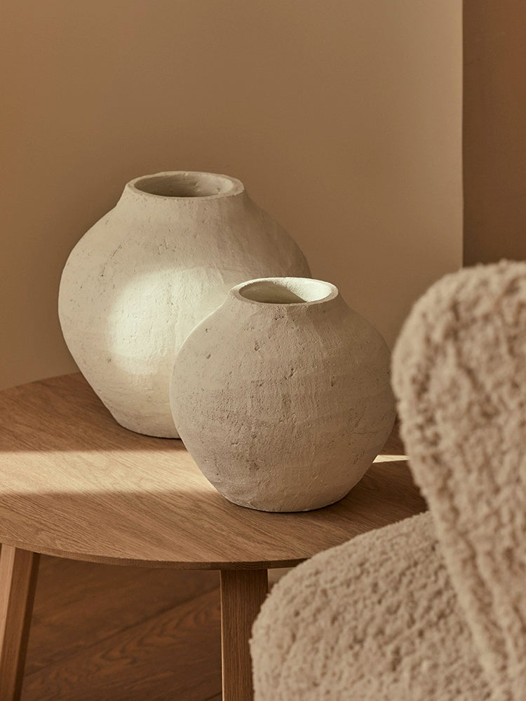 Two textured white ceramic vases, boho style, on a light oak wood coffee table.