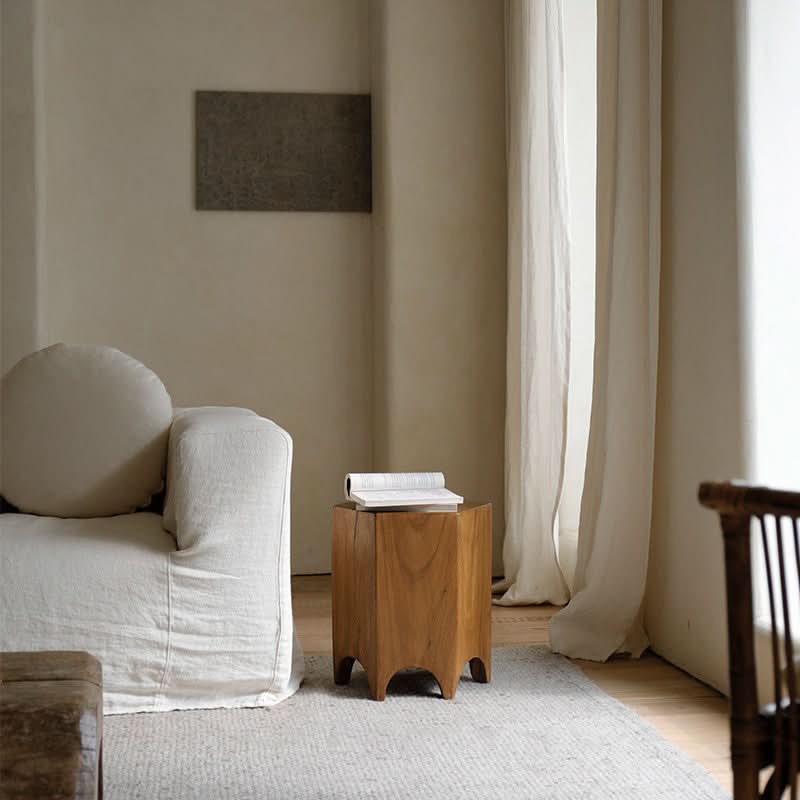 Minimalist wooden hexagonal side table with book, accenting cream sofa and natural decor.