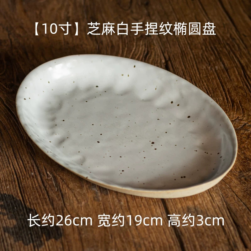 The largest round plate variant, showing a deep, handmade, speckled white serving dish on wood.