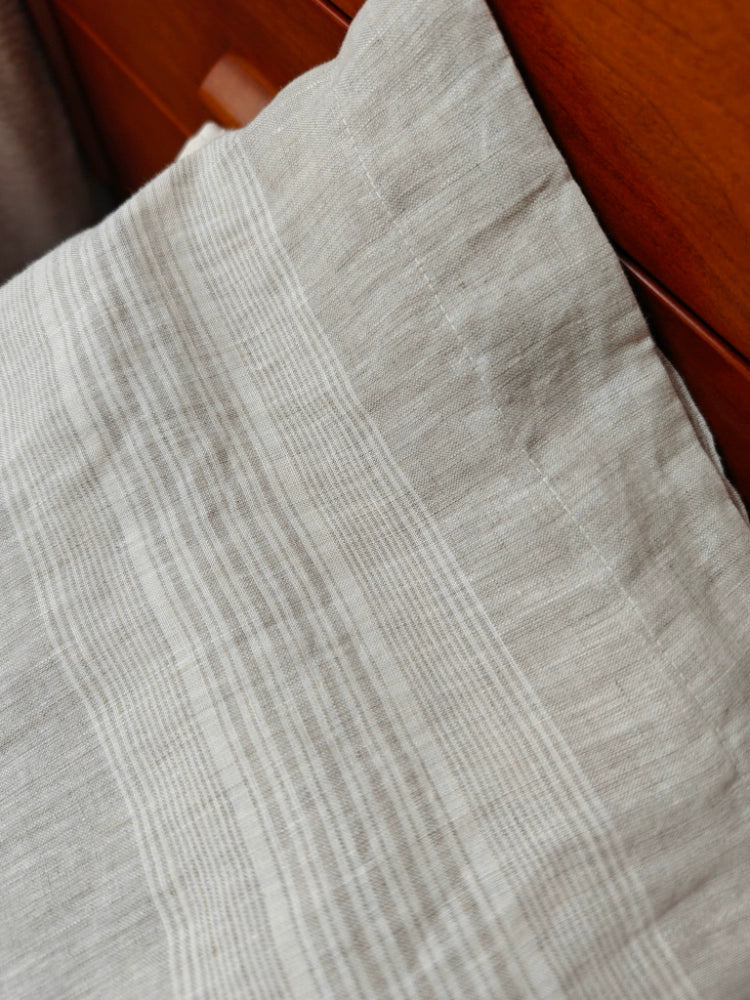 Gray striped linen pillow cover, decorative throw pillow on wooden furniture.
