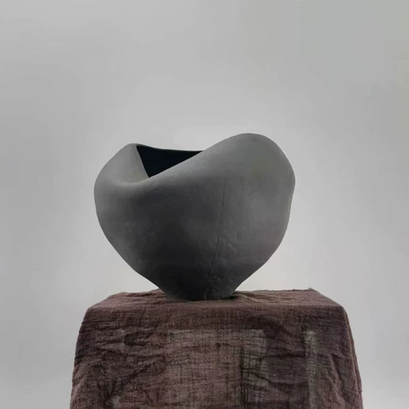 A handmade ceramic vase with a sculptural, folded design and a textured neutral finish.