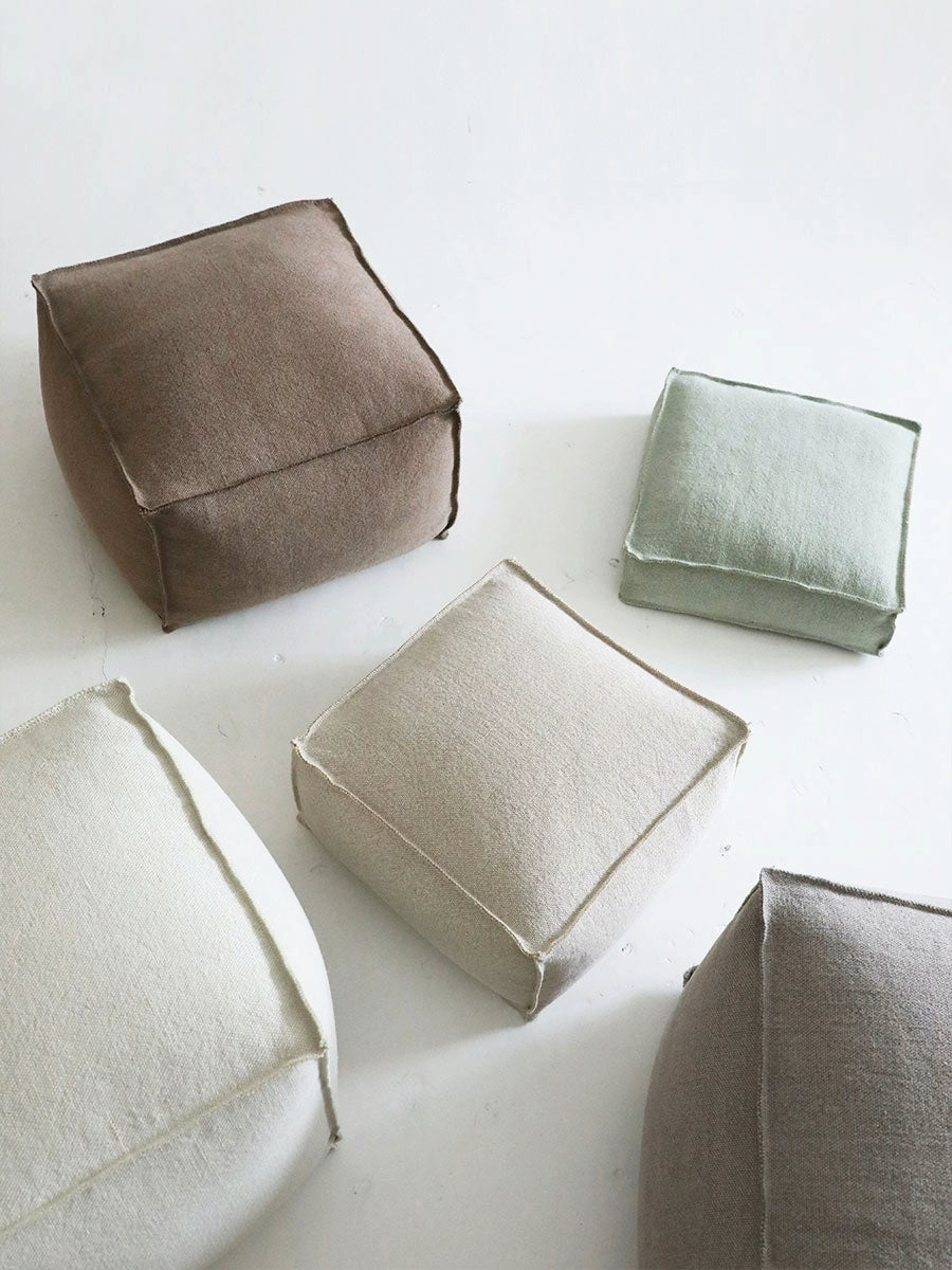 Square knitted poufs in beige, taupe, and cream.  Modern boho style ottomans with visible stitching.