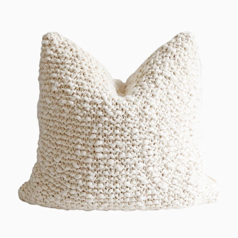 Cream knitted throw pillow, cozy decorative accent for sofa or chair.